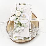 Oryginalna, ręcznie robiona kartka okolicznościowa na Pierwszą Komunię Świętą. Kartka komunijna z motywem lilii oraz białymi kwiatami. Ozdobiona techniką scrapbooking kartka to wspaniała pamiątka komunijna.